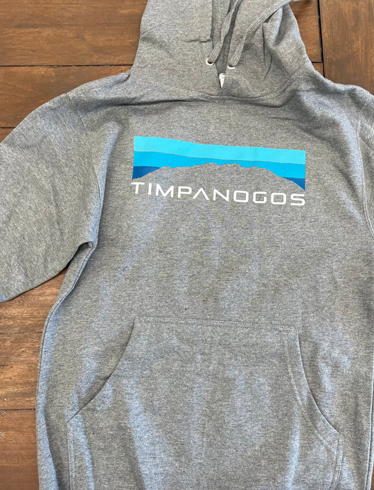 Gray hoodie with 'Timpanogos' logo on a wooden surface