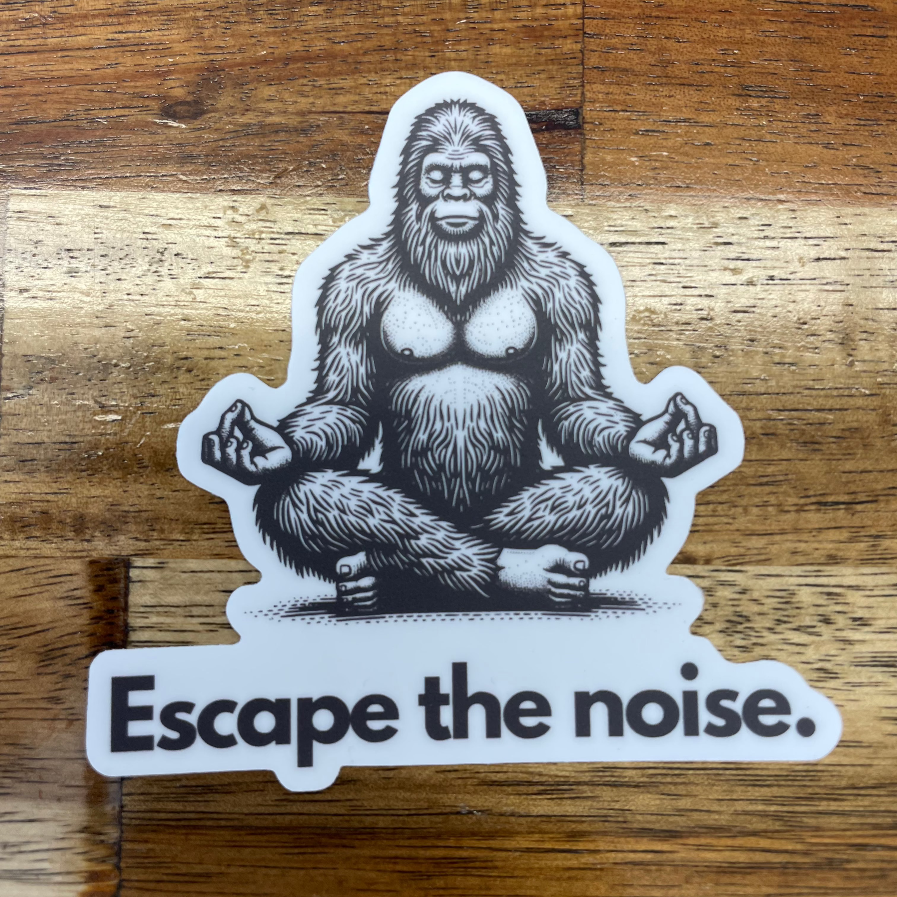 Sticker of a meditating Bigfoot with the phrase "Escape the noise" underneath, perfect for adding a whimsical touch to your gear while embracing the tranquility of nature