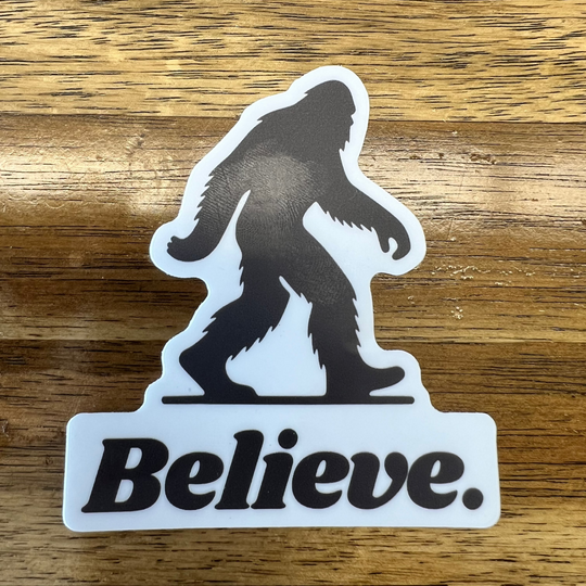 Black and white vinyl sticker featuring a silhouette of Bigfoot walking above bold text that reads "Believe."—a rugged, outdoorsy design perfect for water bottles, coolers, and laptops.