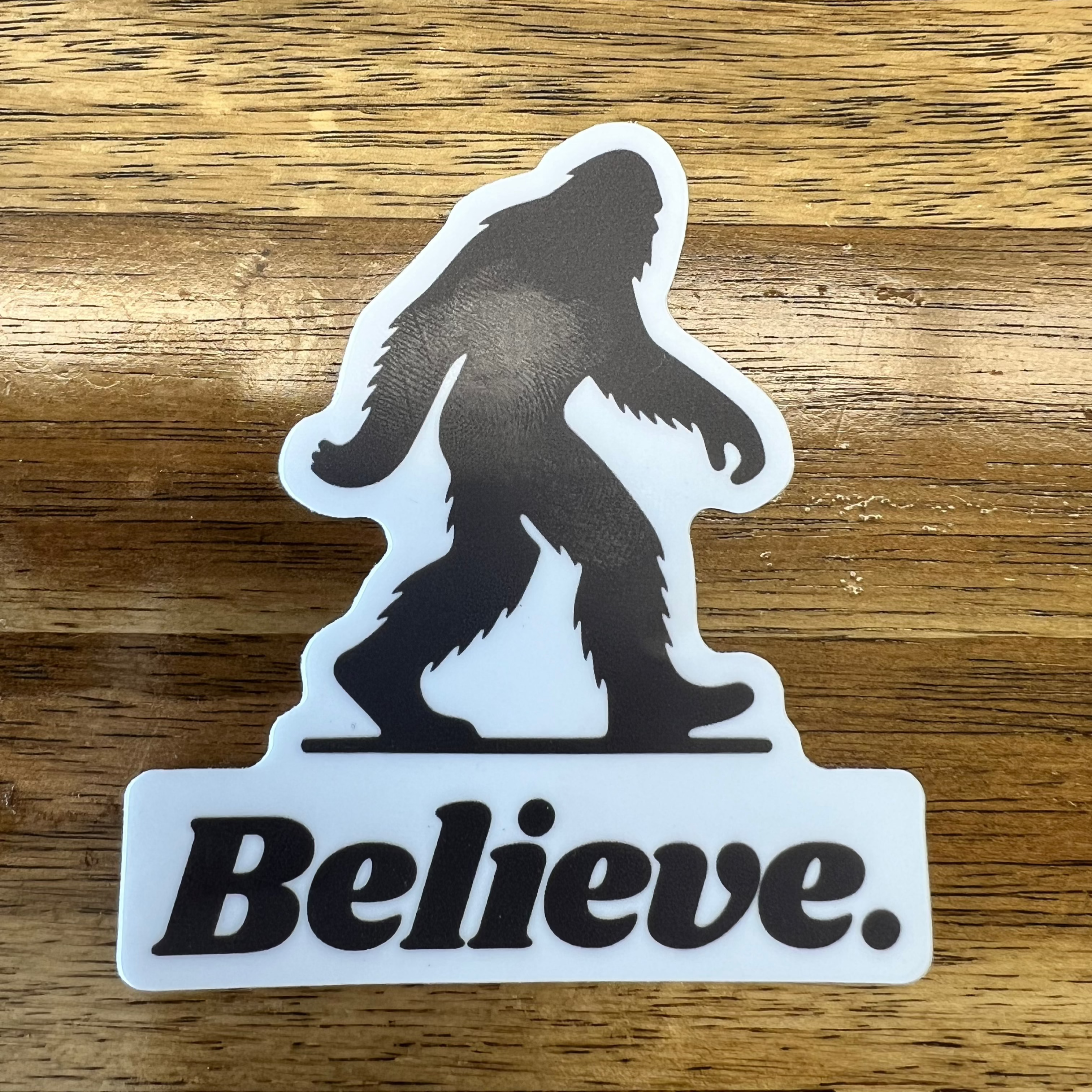 Black and white vinyl sticker featuring a silhouette of Bigfoot walking above bold text that reads "Believe."—a rugged, outdoorsy design perfect for water bottles, coolers, and laptops.
