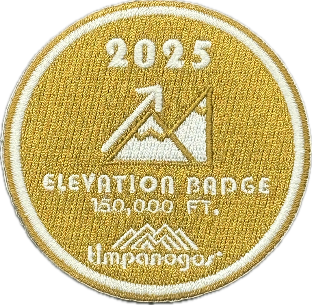 2025 Timpanogos Elevation Badge patch in golden yellow with embroidered white text and graphics, celebrating 150,000 feet of elevation gained. Features mountain artwork with an upward arrow and the Timpanogos Hiking Co. logo.
