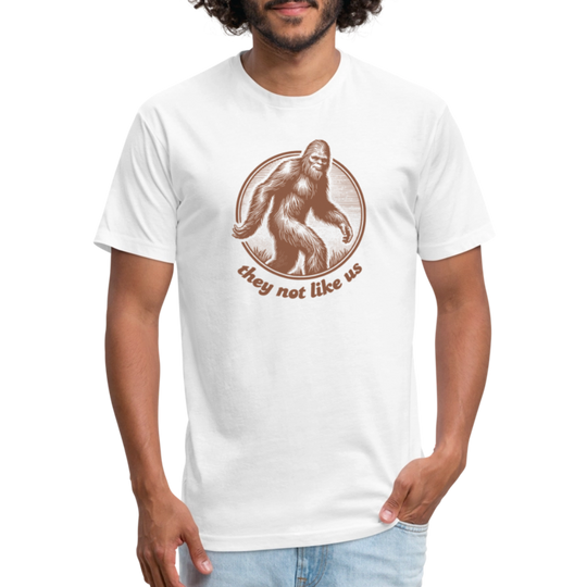 White unisex t-shirt featuring a vintage-style brown illustration of Bigfoot inside a circular frame with the phrase "they not like us" curved below. The design evokes mystery and outdoor adventure with a minimalist, rustic look.