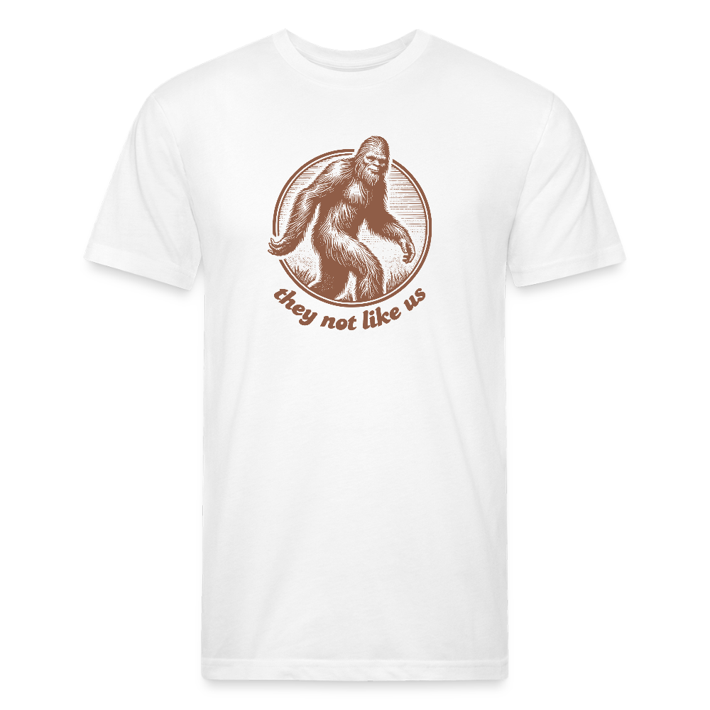 white unisex t-shirt featuring a vintage-style brown illustration of Bigfoot inside a circular frame with the phrase "they not like us" curved below. The design evokes mystery and outdoor adventure with a minimalist, rustic look.