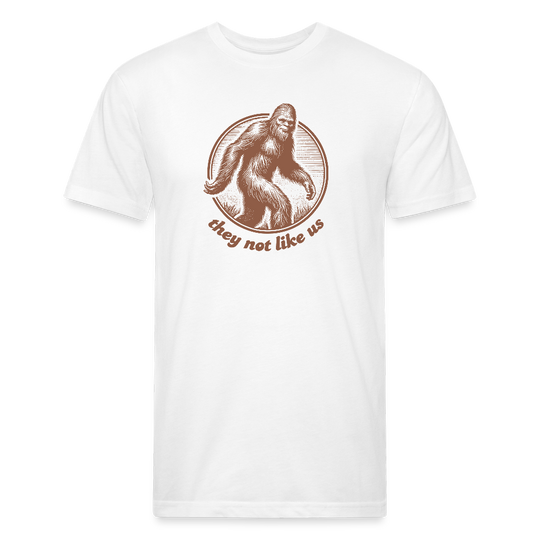 white unisex t-shirt featuring a vintage-style brown illustration of Bigfoot inside a circular frame with the phrase "they not like us" curved below. The design evokes mystery and outdoor adventure with a minimalist, rustic look.